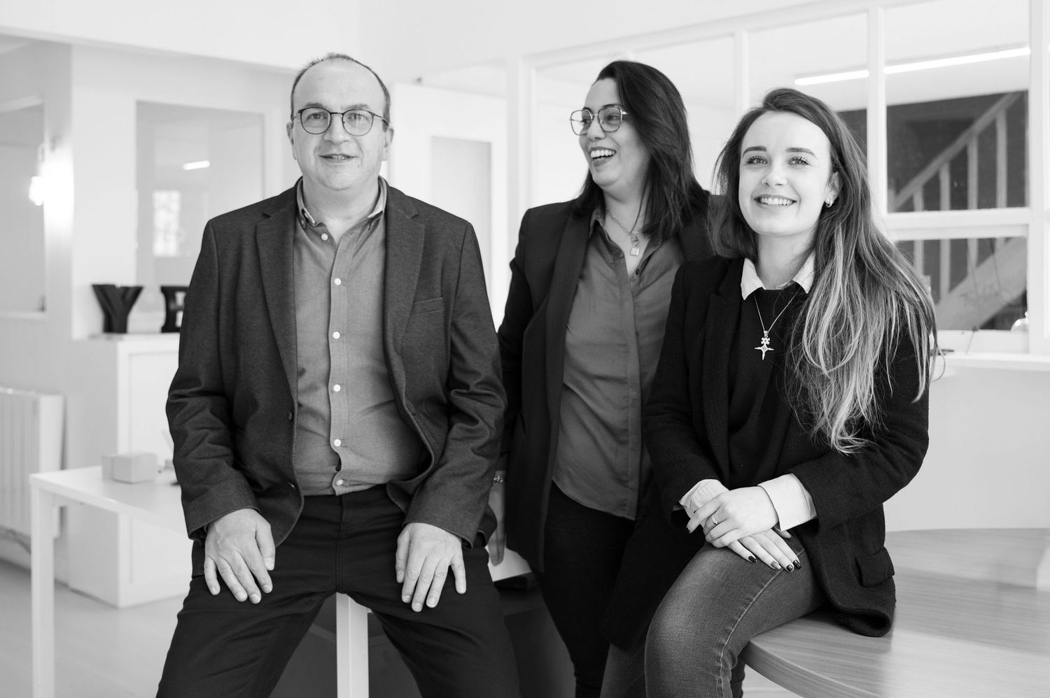 Trois dirigeant·e·s de PME souriants posent dans un bureau moderne, incarnant professionnalisme et cohésion d’équipe.