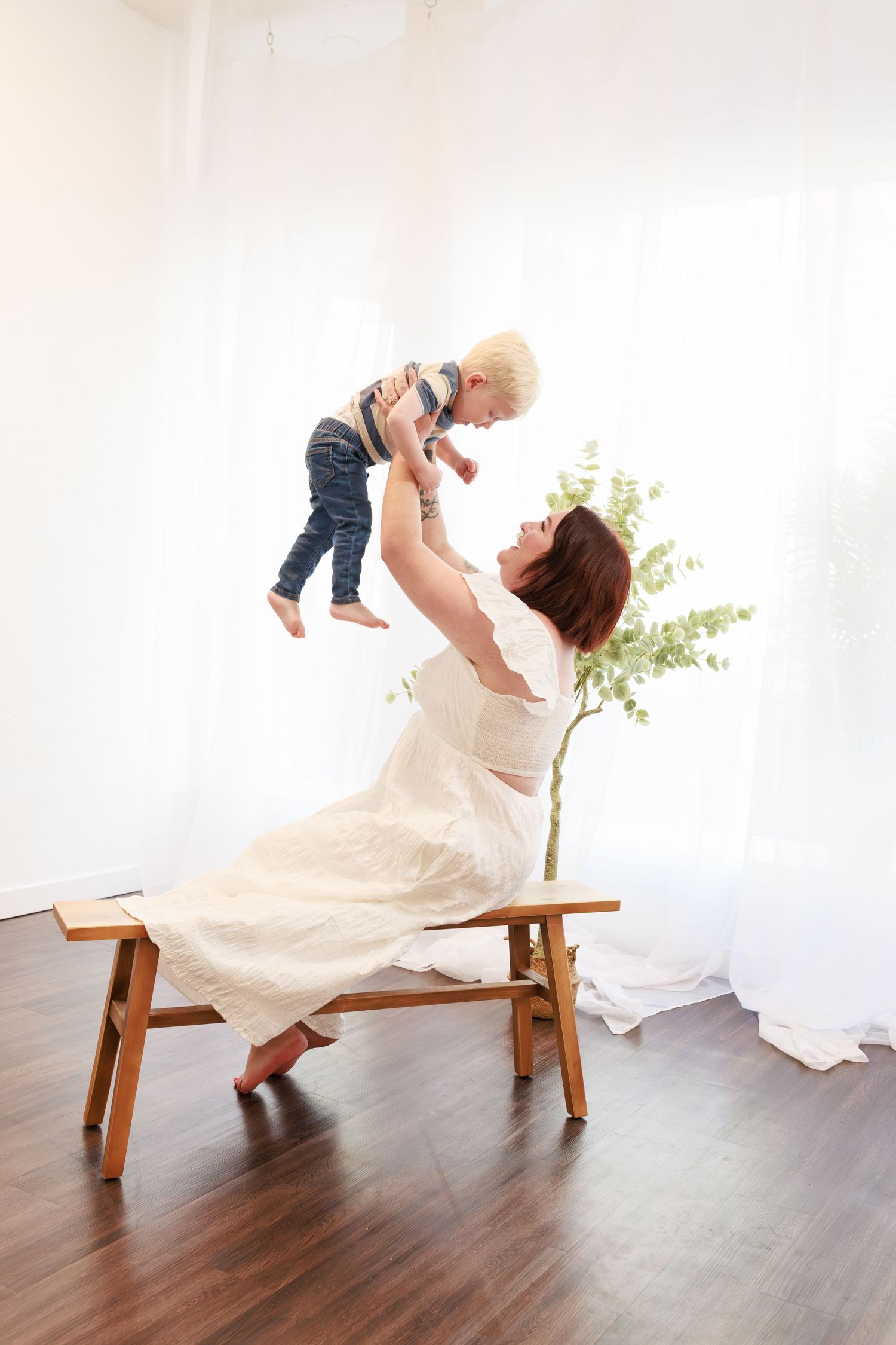 smiling mom tossing her little boy during natural white studio