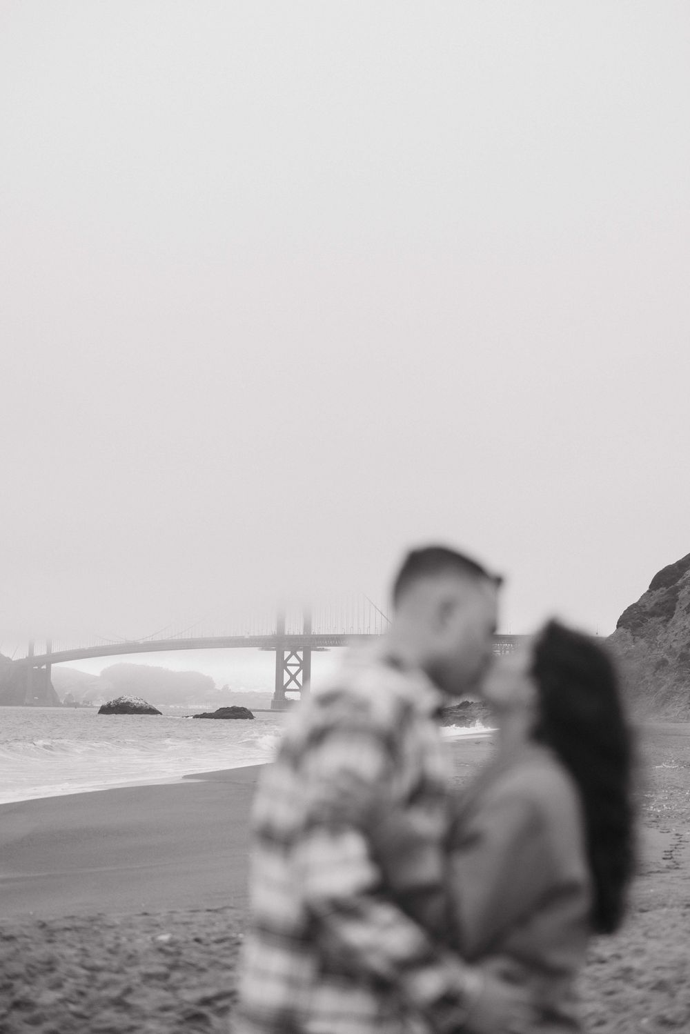 A romantic beach scene overlooking the Golden Gate Bridge in San Francisco with soft focus in black and white.