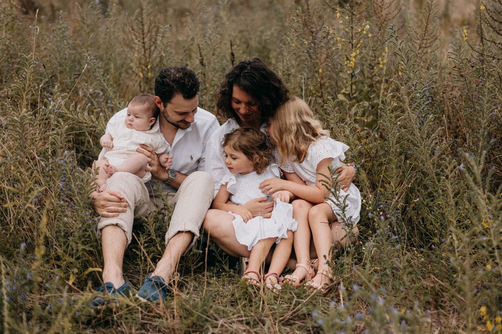 Family gathering outdoors in tall summer grass wearing white clothing.