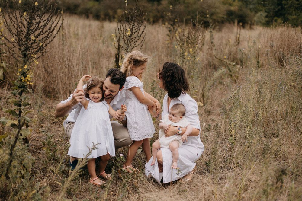 Candid family photograph showing playful interaction between parents and children in natural setting.