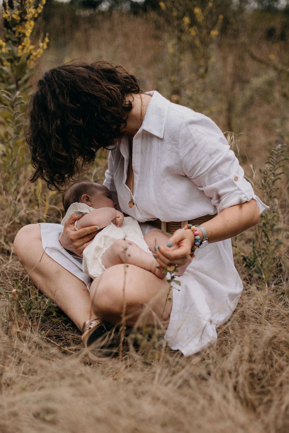 Intimate parenting moment captured in a rustic field setting with soft natural lighting.