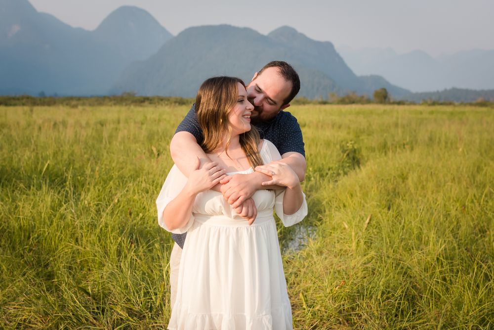 Set in the mountains of Pitt Lake, on a beautiful sunny day, a man wraps his arms lovingly around his fiancee and pulls her in for a hug.