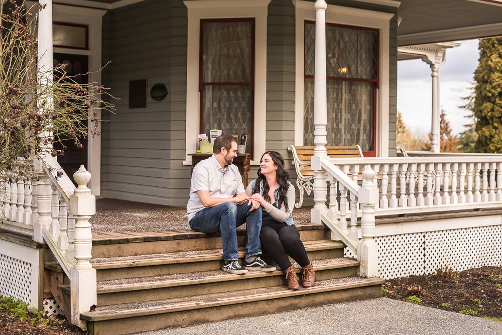 A man and a woman sit on the porch of the historic Stewart Farm in Surrey, BC.