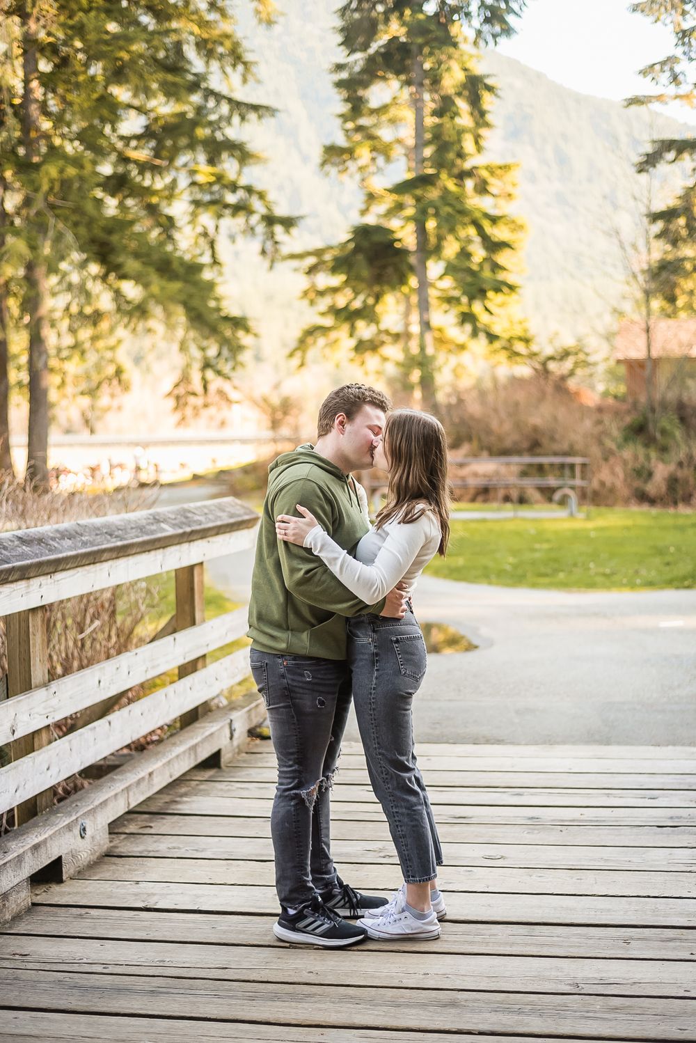 In the beautiful golden sunlight of a pacific northwest forest, a couple embrace for a kiss during their engagement photo session.