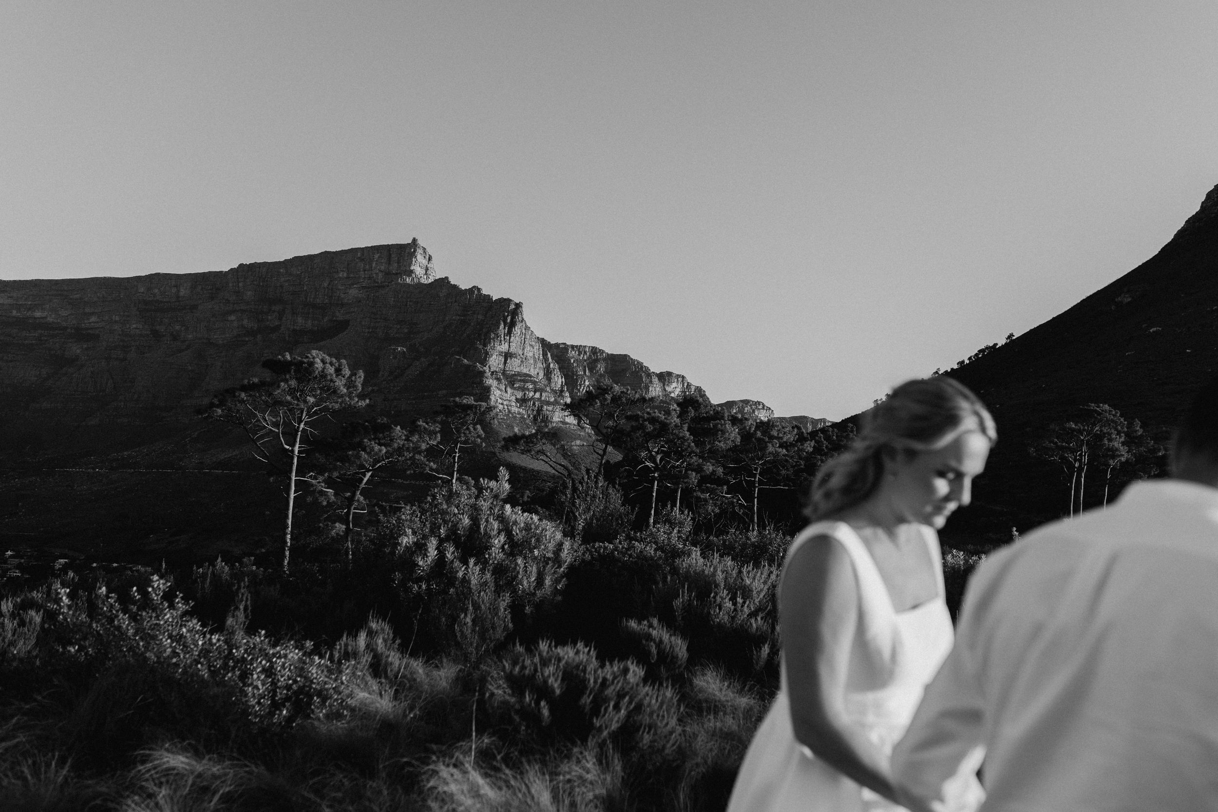 Black and white wedding photo of bride in white dress with Table Mountain backdrop in Cape Town.