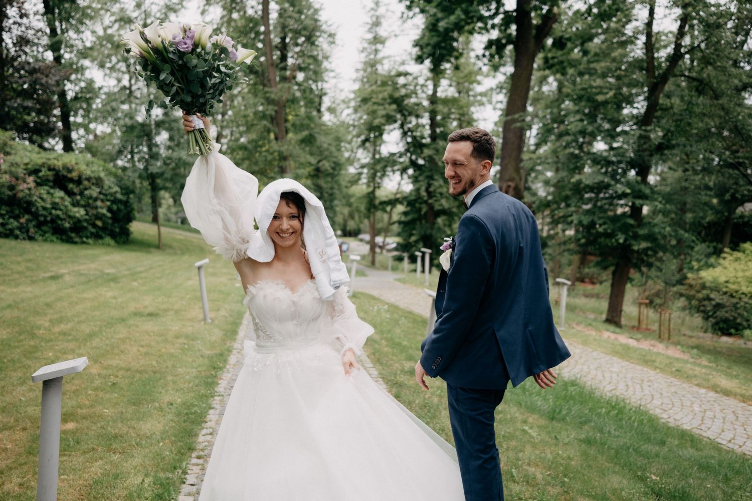 A couple shares a romantic moment on their wedding day in a lush green outdoor garden setting.