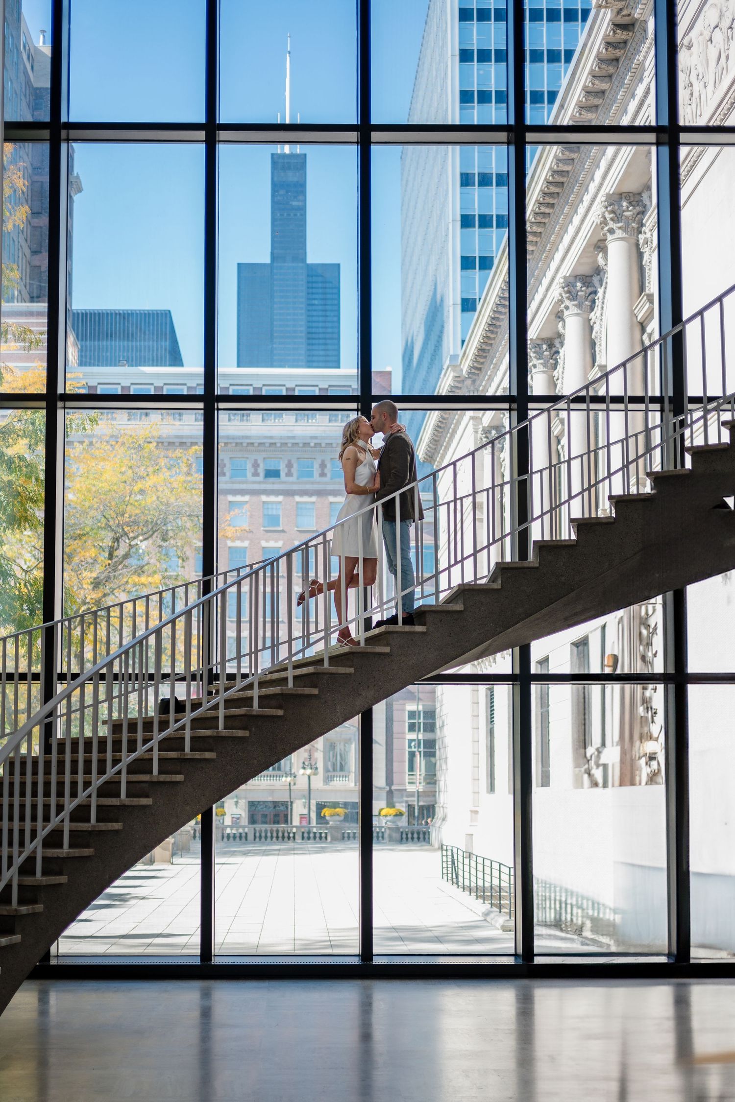 A curved staircase with glass panels and metal railings leads upward in a modern building interior.