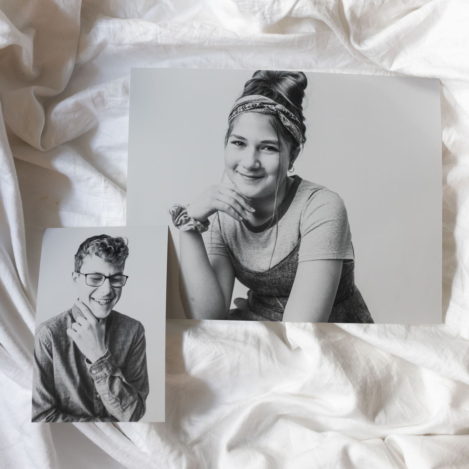 Two vintage black and white portrait photographs displayed on white fabric.