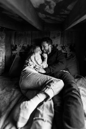 An intimate black and white photo of a couple cuddling in a dimly lit indoor setting.