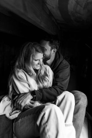 Black and white intimate portrait of a couple sharing a tender moment in dramatic lighting.