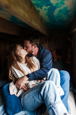 A romantic couple sharing an intimate moment in casual attire against a moody dark background.