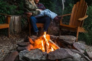 A cozy evening scene with a roaring campfire and Adirondack chairs.