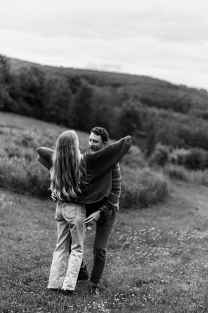 Two people share a romantic dance together in a wildflower field with mountains behind them.