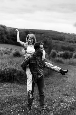 A playful couple enjoying a carefree moment in a mountain meadow, captured in black and white.