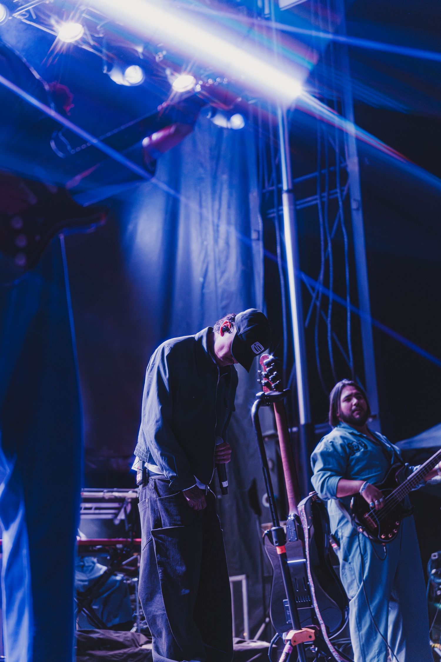 Musicians perform on a dimly lit stage bathed in blue lighting during a live concert performance.