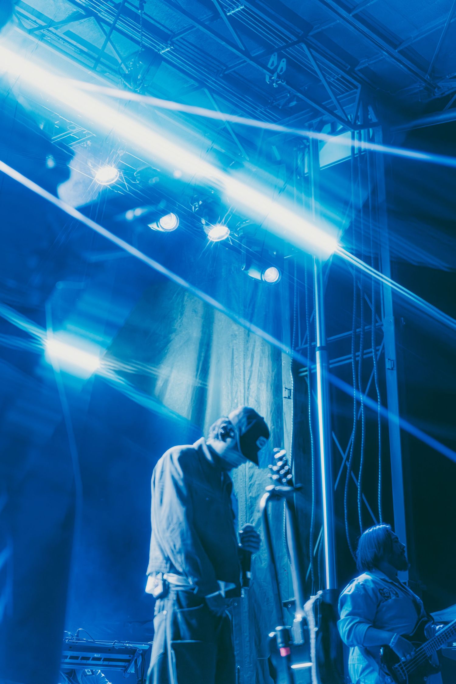 Silhouetted performer on stage bathed in dramatic blue lighting during a live music concert performance.