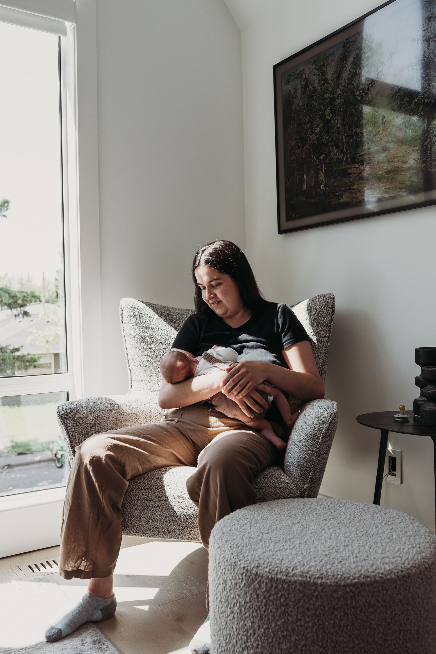 mom quietly nursing her newborn in the sunshine in a cozy chair in her home