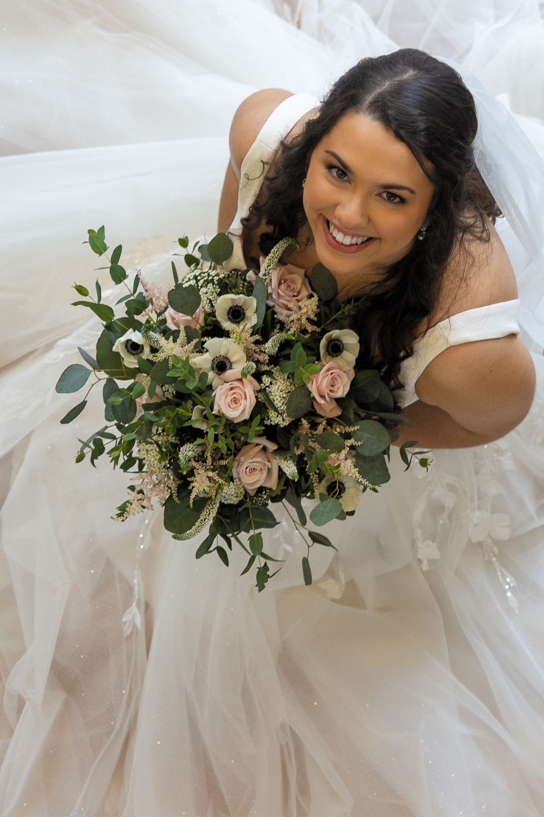 A bride in a white wedding dress holds a romantic bouquet of dusty pink roses and eucalyptus greenery in a series of poses.