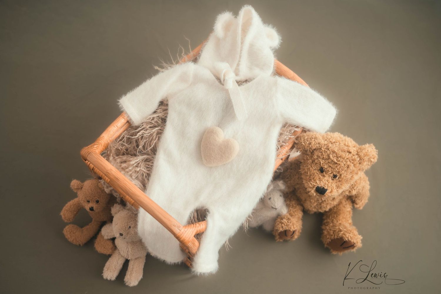 Cute white bunny newborn outfit with a heart detail displayed in a wooden crate with teddy bears. Newborn Photography by K Lewis Photography