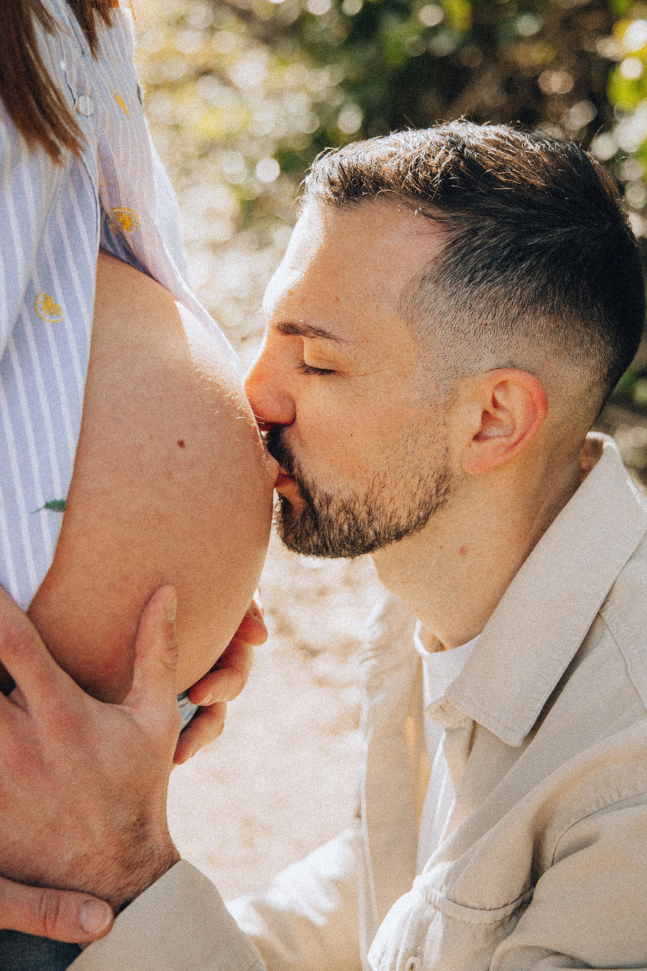 Papa déposant un baiser tendre sur le ventre arrondi de la future maman, en pleine nature à Toulouse
