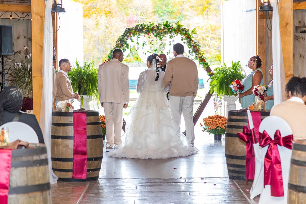 Wedding ceremony guests seated in an elegant indoor venue with pink floral decorations and natural lighting.