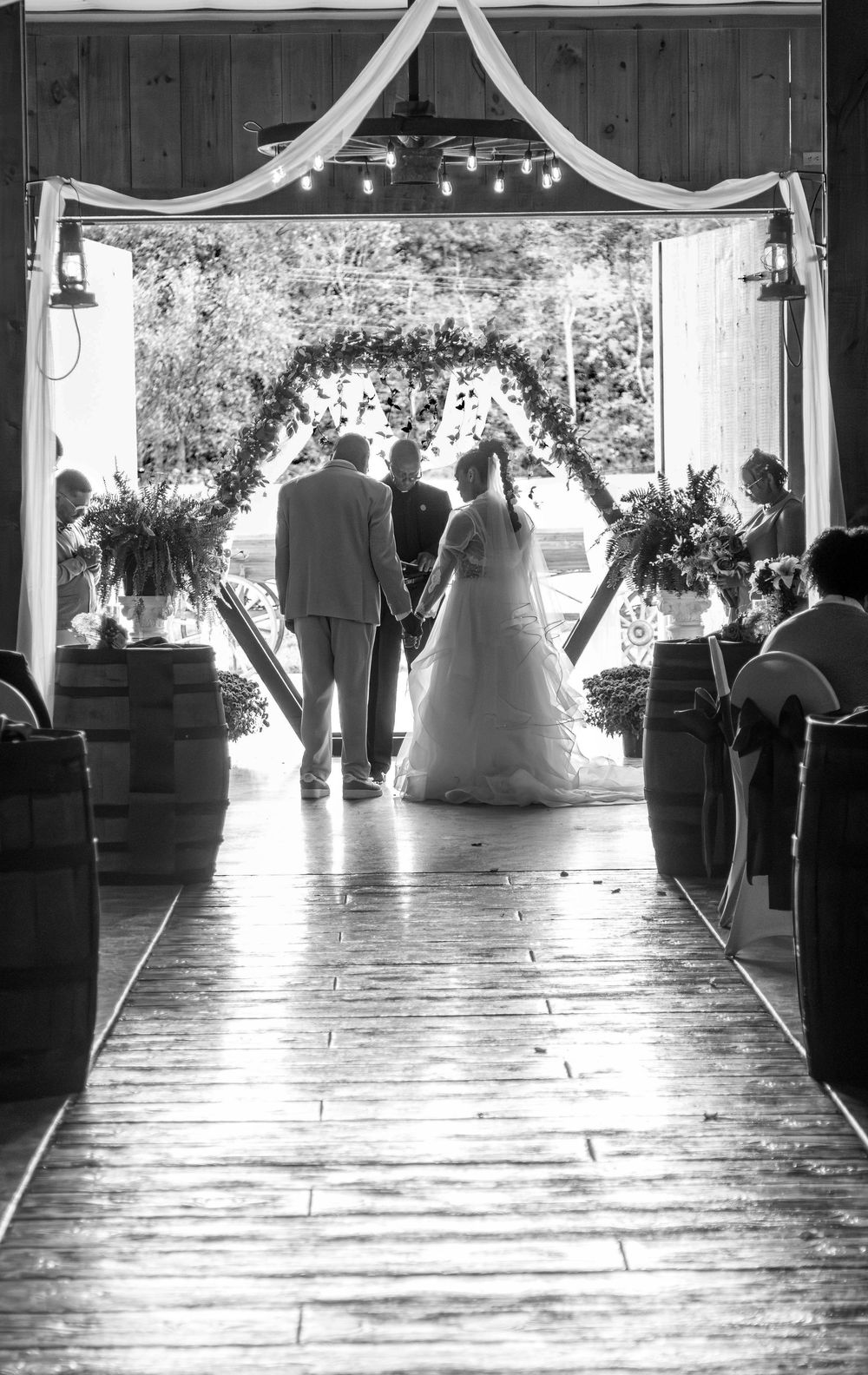 A wedding ceremony sequence showing the progression of a bride walking down a rustic barn aisle decorated with string lights.