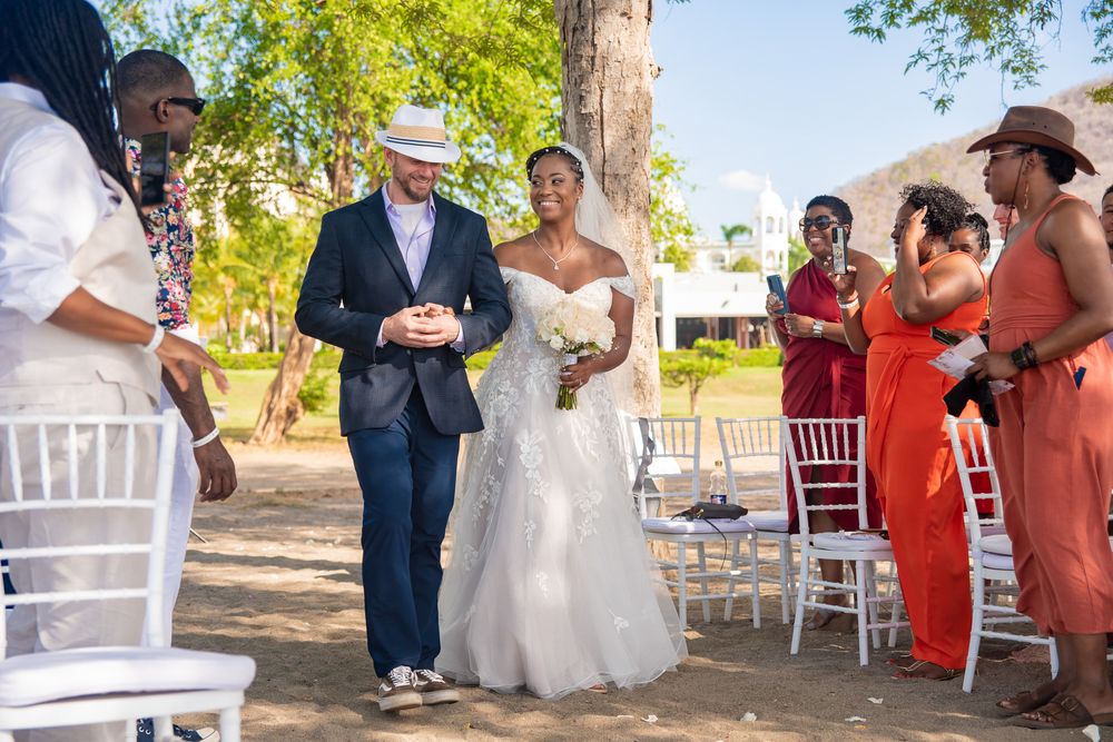 Wedding ceremony guests seated in white chairs under shady trees at an outdoor venue in Riu Place, Costa Rica