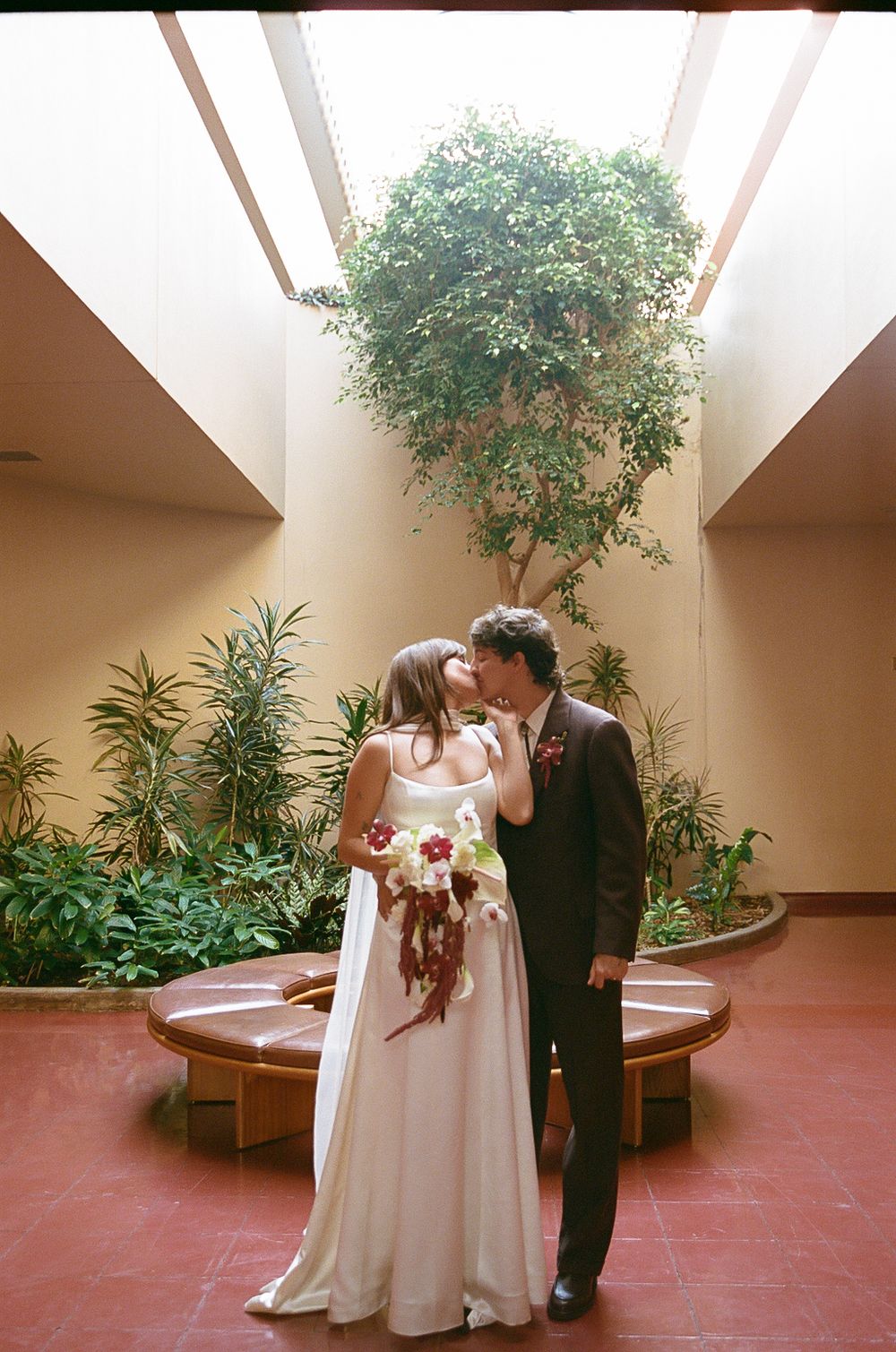 Wedding couple poses together in a courtyard garden with terracotta floors and potted plants.