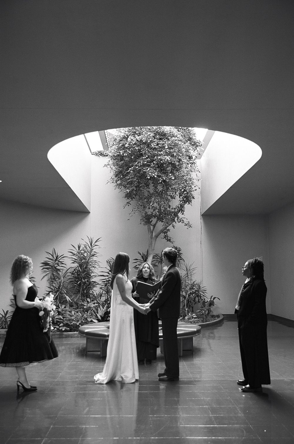 Black and white wedding ceremony photos in a modern interior space with dramatic lighting.