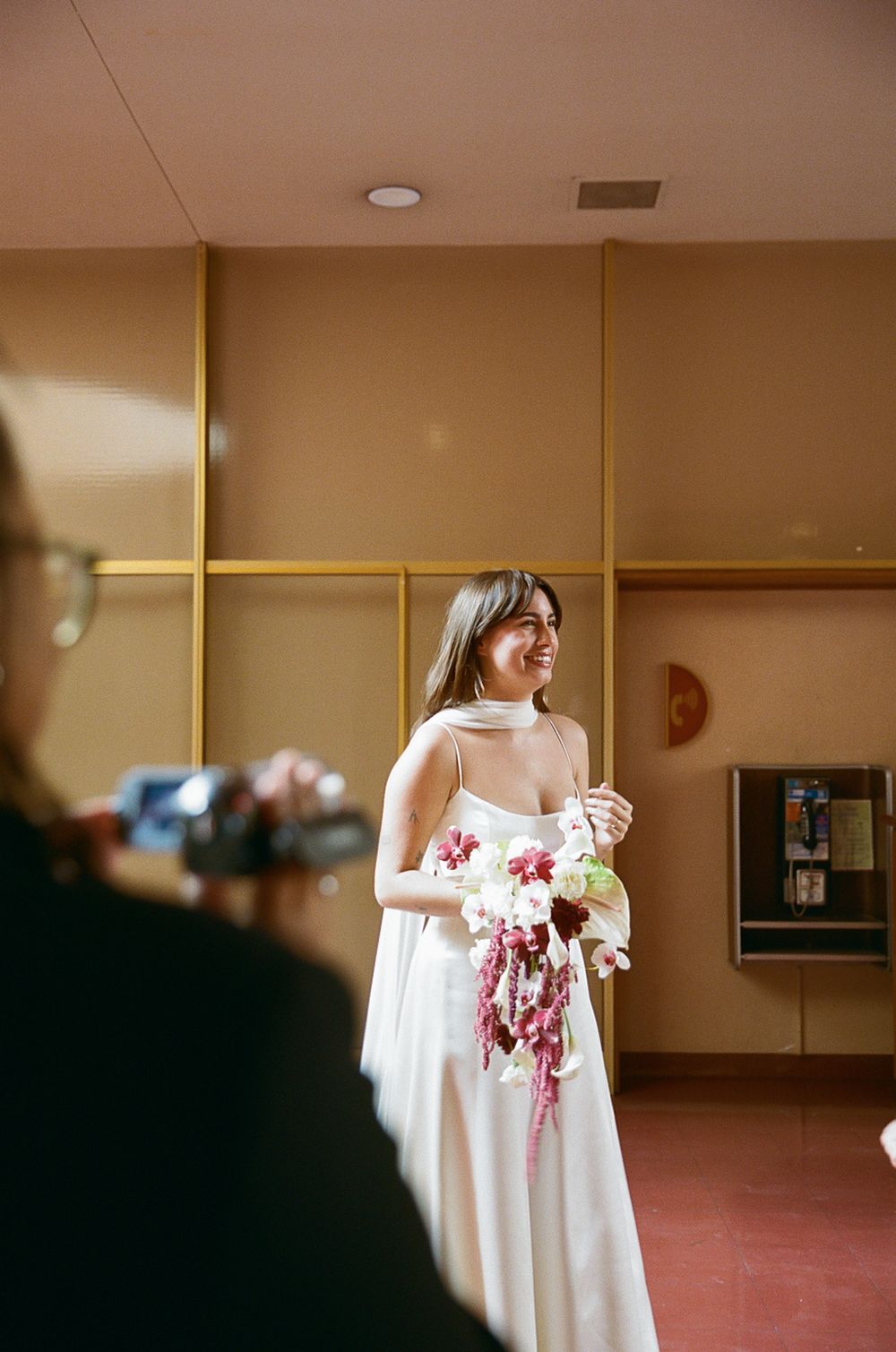 Wedding preparations in a hallway with elegant white gowns and floral bouquets.