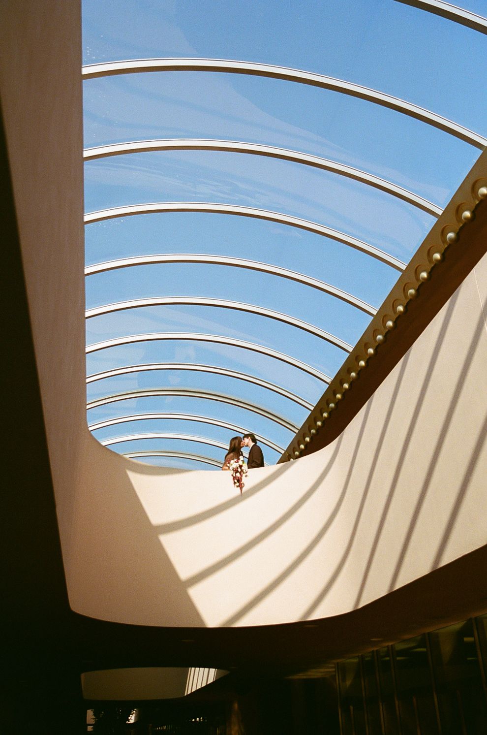 Modern architecture with curved white beams and skylights creating dramatic shadows in a contemporary space.