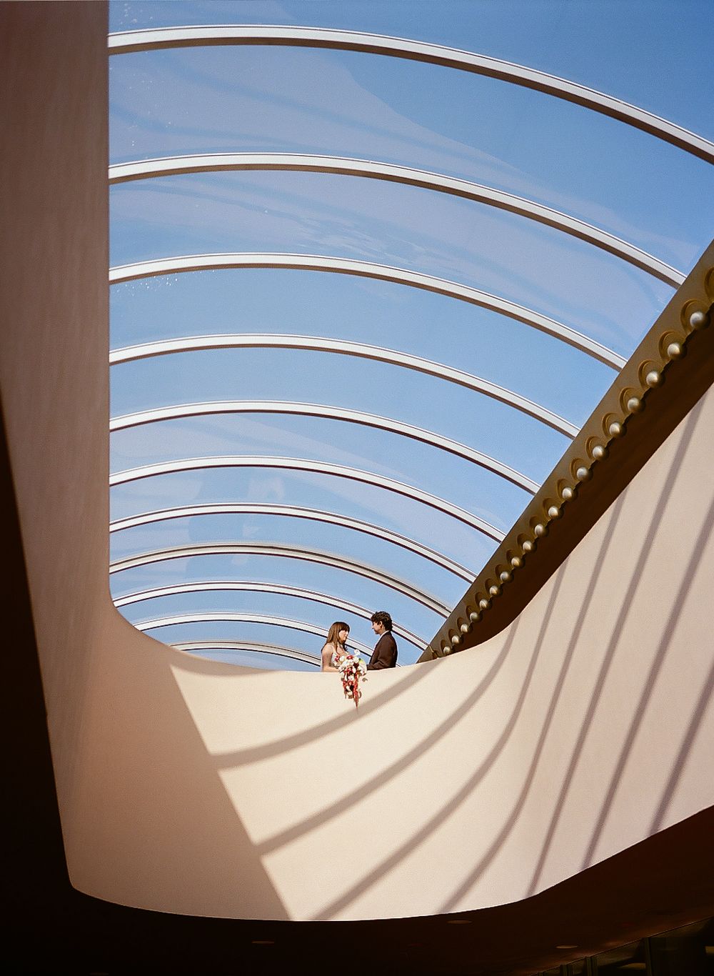 Architectural shot of curved white walls and arched ceiling creating dramatic lines against blue sky.