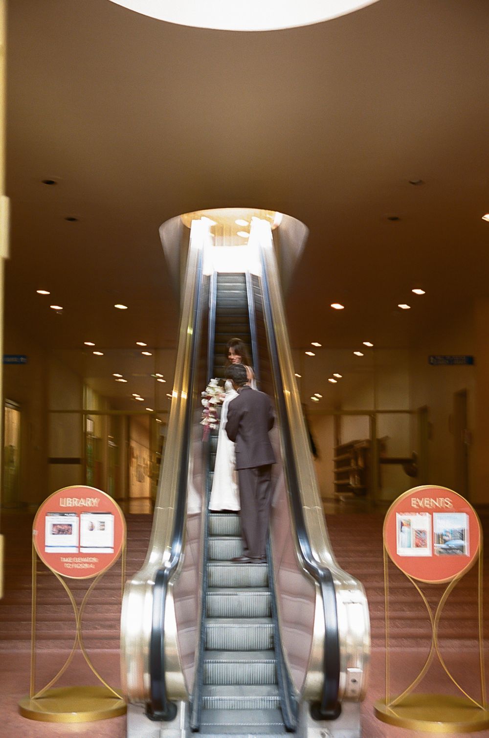 Modern escalators in a commercial building interior with circular red signage.