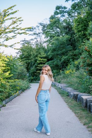 Full length casual portrait on garden path wearing denim and white top.