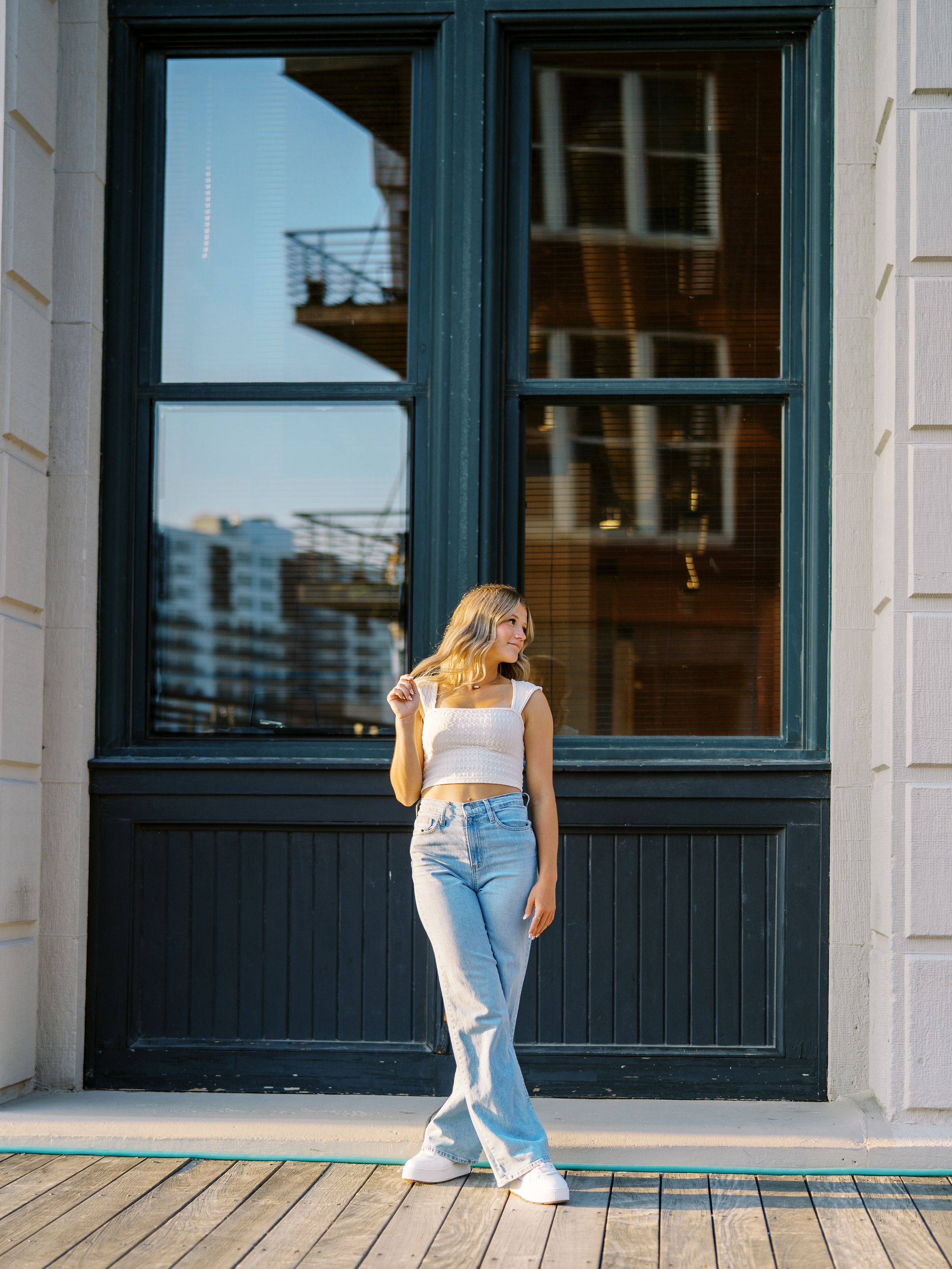 Lifestyle fashion photos on wooden deck with blue-framed windows and urban backdrop.
