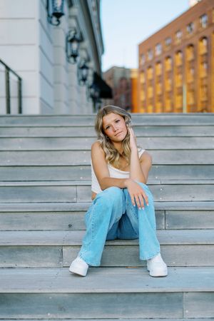 Fashion photography on concrete steps featuring casual denim style against city backdrop.