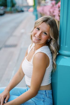 Casual portrait against turquoise column wearing summer outfit in urban setting.