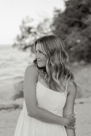 Black and white portrait with soft waves and natural lighting against a coastal background.