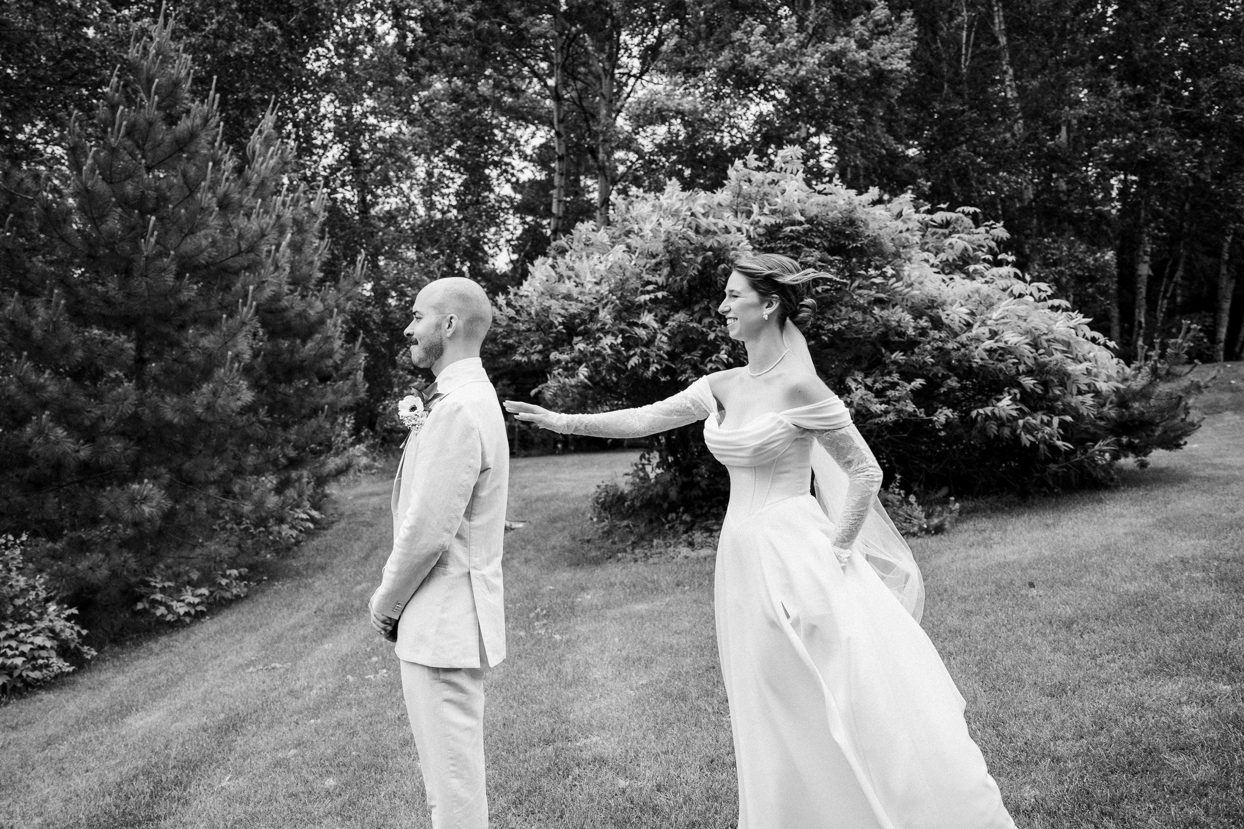 A couple shares a playful moment on a garden path during their wedding celebration in black and white photography.