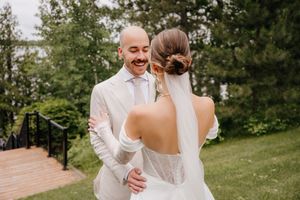 A couple shares a joyful moment together outdoors during their wedding, with the bride in a white dress and groom in white attire.