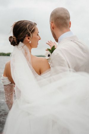 A romantic wedding couple dances outdoors as the bride's white veil flows elegantly in the wind.