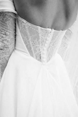 Close-up black and white detail of delicate lace bodice on a wedding dress showing intricate floral patterns.