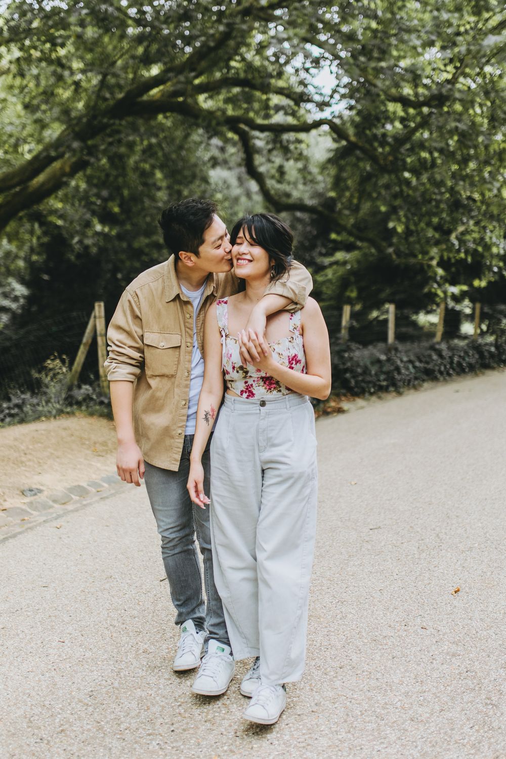 A sweet outdoor moment captured on a tree-lined path showing genuine affection and joy.