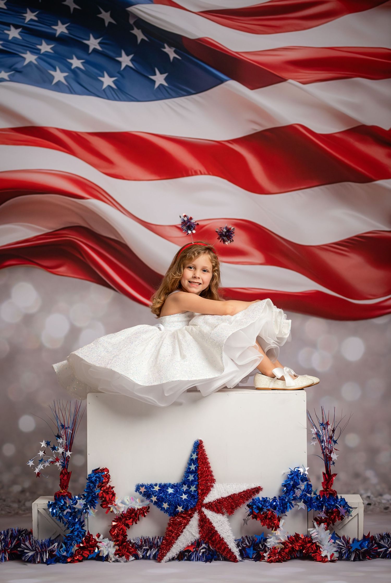 American flag waves majestically above patriotic red white and blue star decorations with white box display.