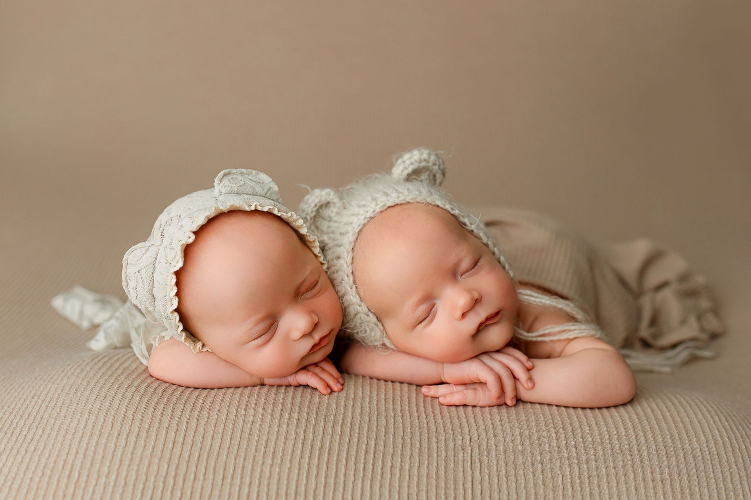 Newborn twins in white knit bear ear hats posing on chins in Flowertown Photography Studio in Summerville, SC