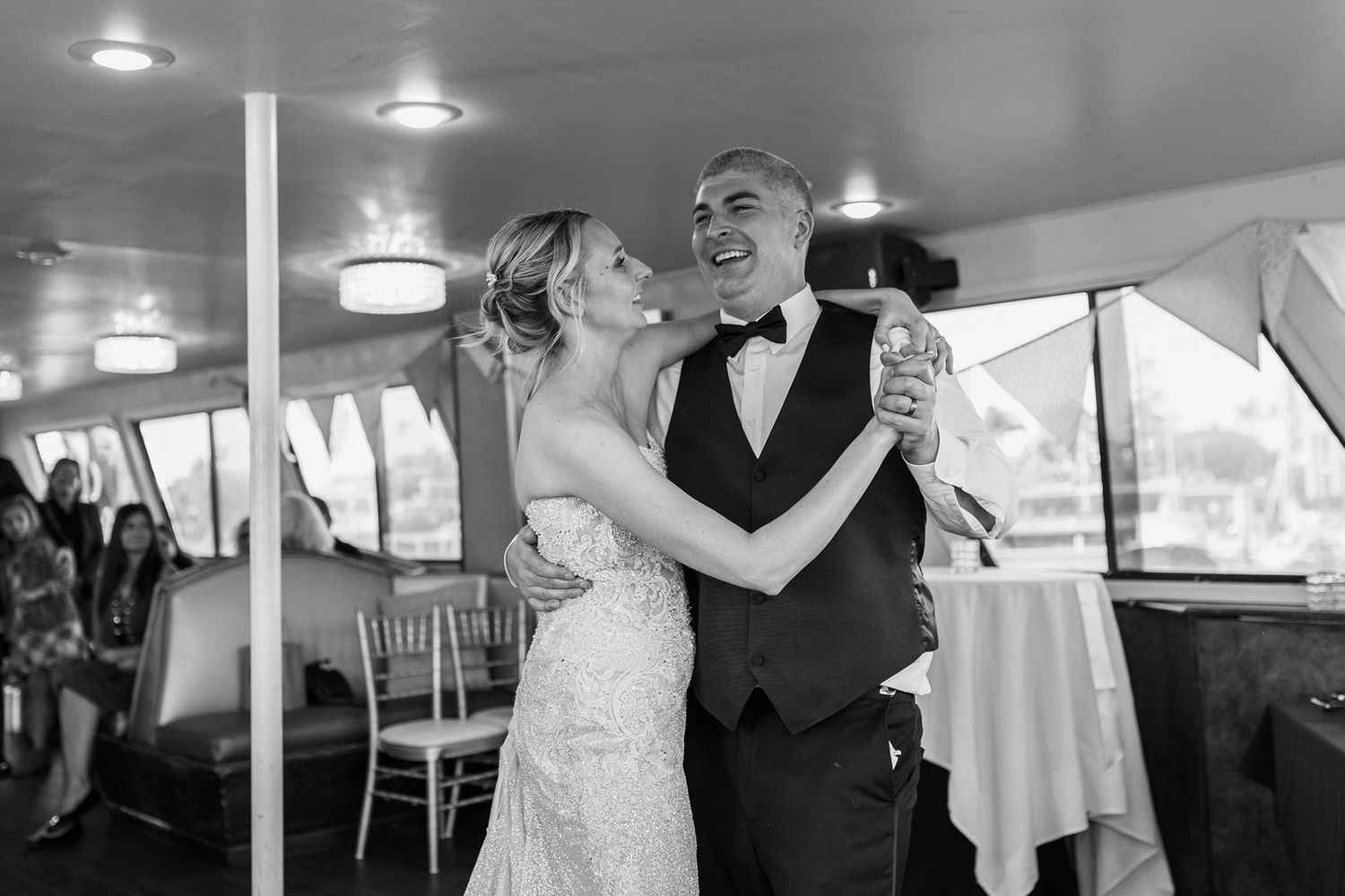 A couple shares their first dance together at an elegant indoor wedding reception venue on a boat in San Diego.