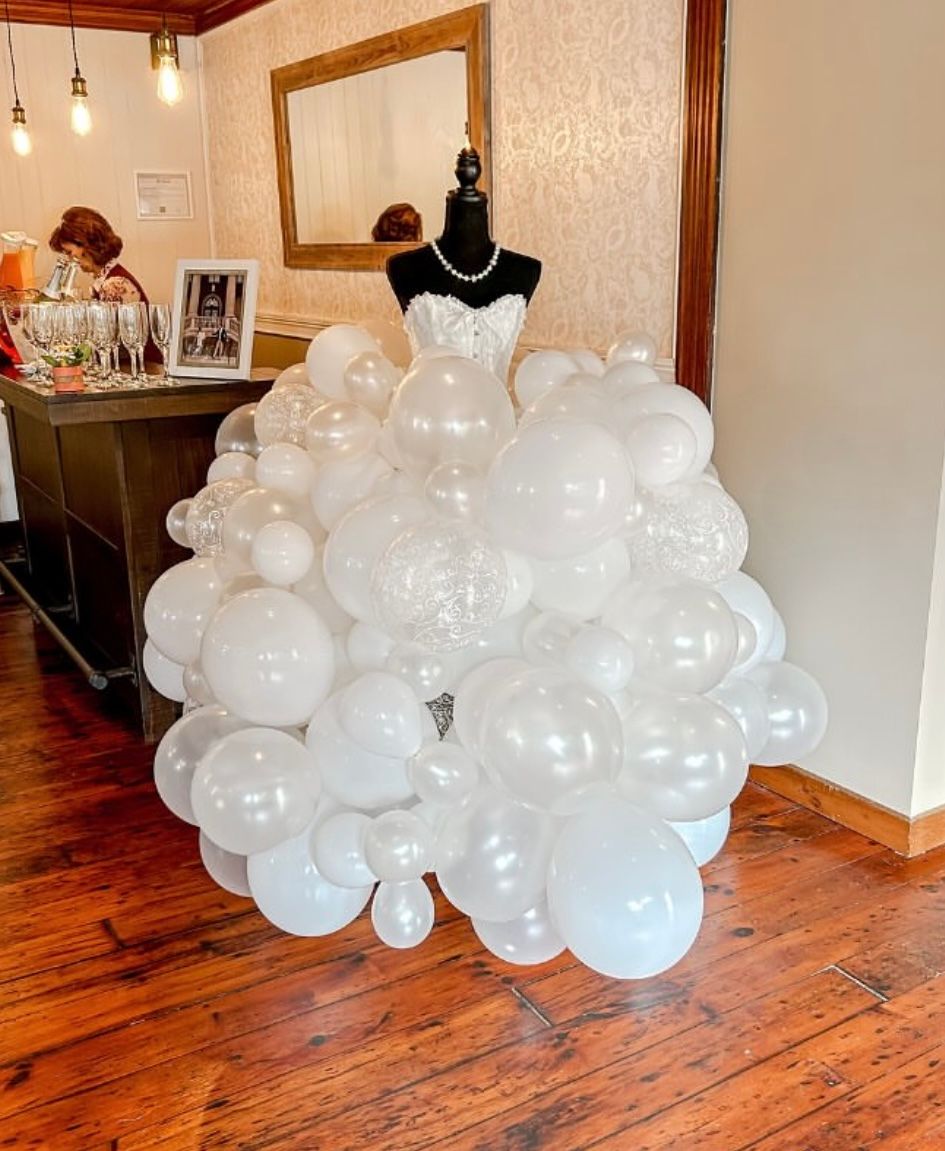 Creative wedding dress display made entirely of white balloons on a mannequin in an event venue.