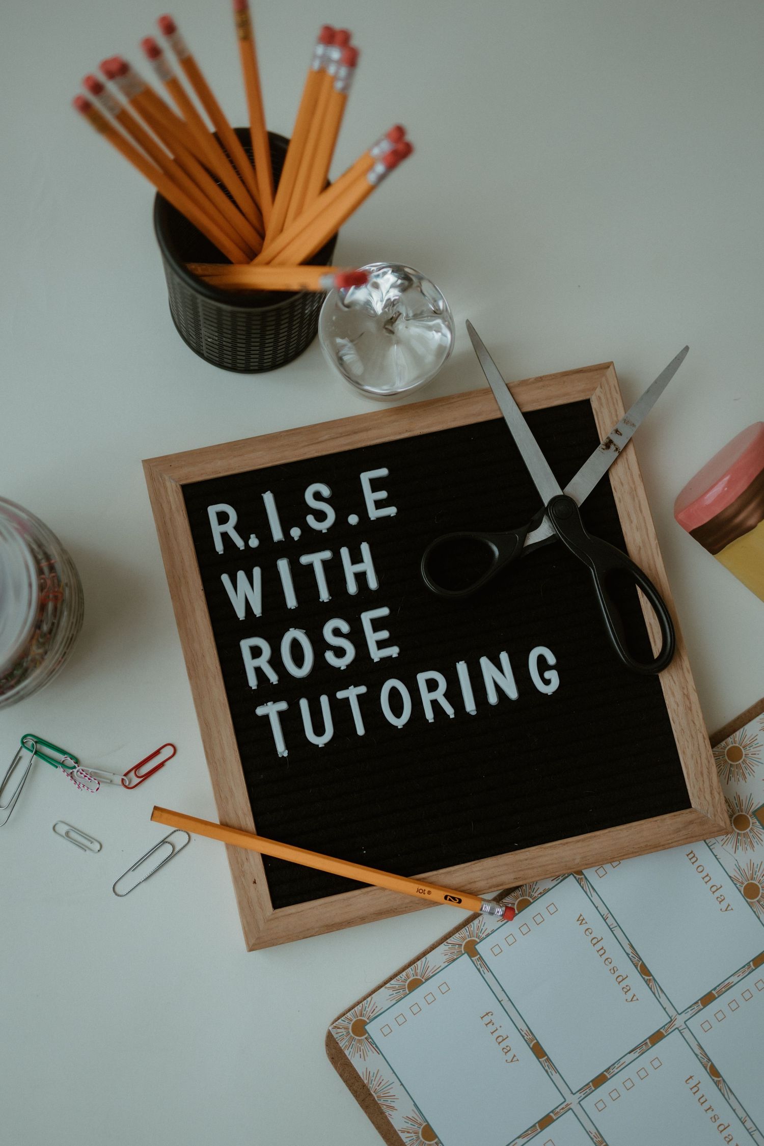 A series of chalkboards displaying text about tutoring with pencils and papers scattered around them on a white surface.