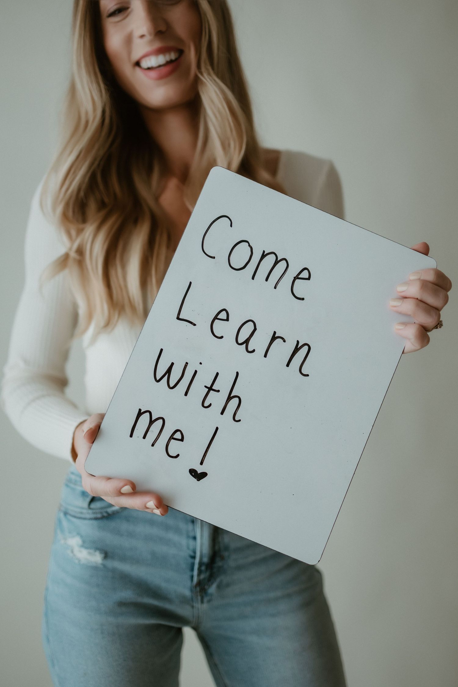 A series of photos showing someone holding up handwritten signs with text while wearing a white top and jeans.